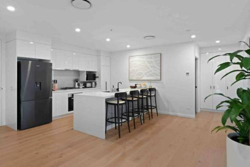 a kitchen with white cabinets and a black refrigerator at New 3 Bed Penthouse Resort style complex in Brisbane