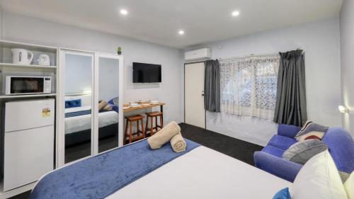 a living room with a blue couch and a bed at Parkes Federation Motel in Parkes
