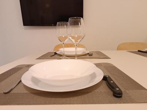 a white plate and two wine glasses on a table at il 64B - 10 minuti a piedi dal Policlinico San Matteo - in Pavia