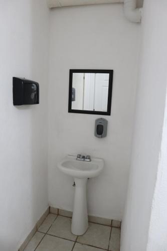Baño blanco con lavabo y espejo en Hostal Purísima, en San Francisco del Rincón