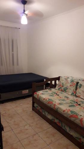 a bedroom with two twin beds and a fan at Lindo apartamento em frente a praia in Praia Grande