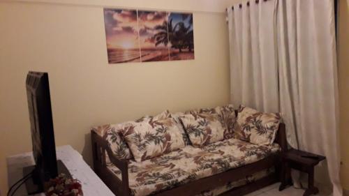a couch in a living room with a picture on the wall at Lindo apartamento em frente a praia in Praia Grande