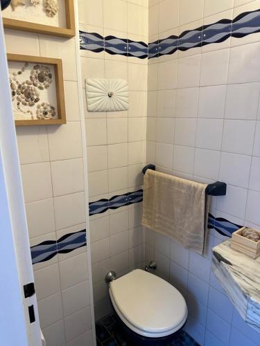 uma casa de banho com um WC branco e azulejos azuis e brancos. em Lujo Junto al Mar - Cochera y Terraza Privada em Mar del Plata