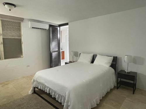 - une chambre avec un grand lit blanc et une fenêtre dans l'établissement CasaMar House Whit Pool 3 Bedrooms 3 Bathrooms, à San Juan