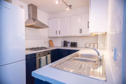 Spacious 1 Bed- Nunhead/Peckham-sleeps 4 في لندن: مطبخ أبيض مع حوض وموقد