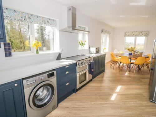 Una cocina con gabinetes azules y una mesa con sillas. en Orchard House, en Leominster