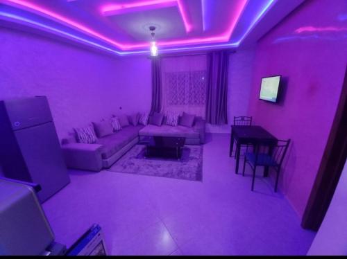 ein lila Wohnzimmer mit einem Sofa und einem Tisch in der Unterkunft Appartements ESSALAM 1 in El Aaiún