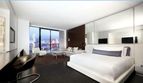 a bedroom with a large white bed and a living room at Fantastic palms place with strip views 23rd floor in Las Vegas