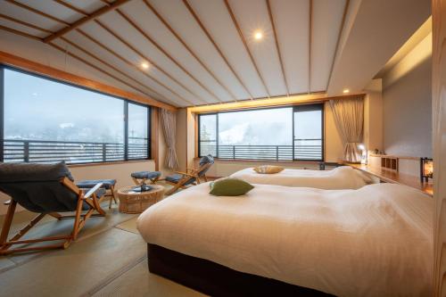 um quarto com 2 camas e uma grande janela em Iwashimizu Ryori no Yado Kinosato em Zao Onsen
