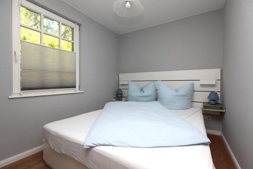 a bedroom with a white bed and a window at Strandnest in Wustrow