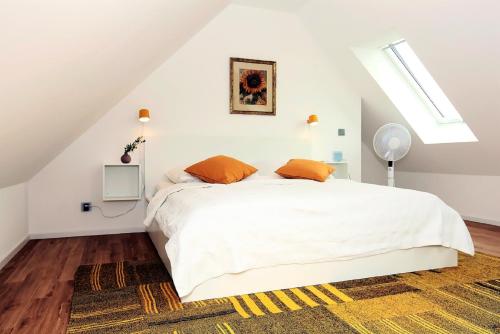 a white bedroom with a white bed with orange pillows at FeWo Bark Middenmang in Wustrow