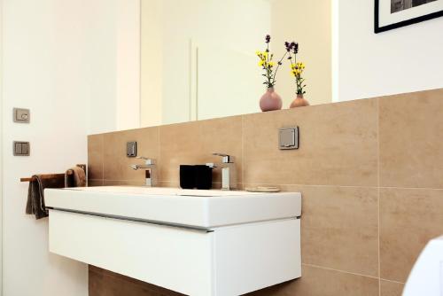 a white bathroom sink with two vases on the wall at FeWo Bark Middenmang in Wustrow
