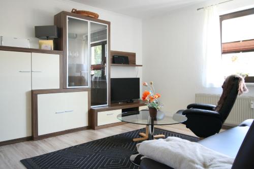ein Wohnzimmer mit einem Glastisch und einem TV in der Unterkunft Strandläufer in Wustrow