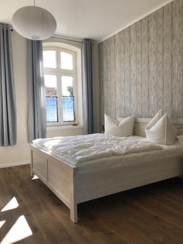 een slaapkamer met een groot wit bed en een raam bij Villa Martha FW Erika in Wustrow