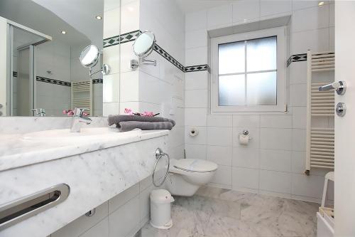 La salle de bains est pourvue de toilettes, d'un lavabo et d'un miroir. dans l'établissement Haus Kranich App 426, à Neuhaus