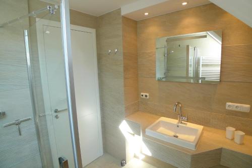 a bathroom with a sink and a shower with a mirror at Haus Dünenrot OG-Whg DR-04 in Neuhaus