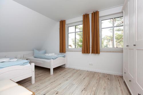 a white room with a bed and two windows at Haus Eichkater in Dierhagen
