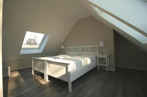 een witte slaapkamer met een bed en een raam bij Haus Strandkieker Whg 4 in Neuhaus