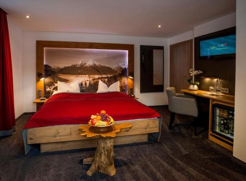 Schlafzimmer mit einem großen roten Bett und einem Schreibtisch in der Unterkunft Hotel Brunneck in Schönau am Königssee