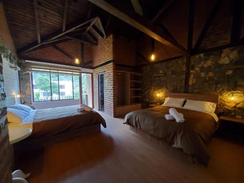 巴尼奧斯的住宿－La Quinta Mansión Lofts，一间卧室设有两张床和石墙