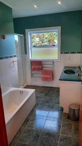 uma casa de banho com uma banheira, um lavatório e uma janela em Greenfield Country Homestay em Pukeawa