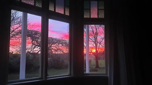 a window with a view of a sunset seen through it at Greenfield Country Homestay in Pukeawa