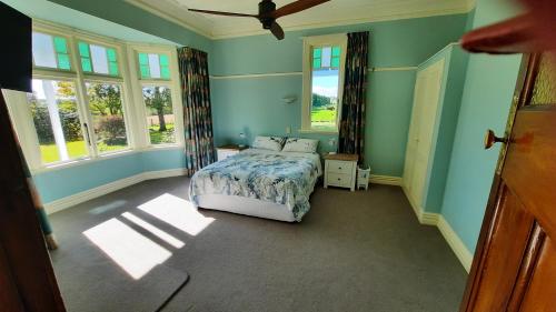 a bedroom with a bed in a room with windows at Greenfield Country Homestay in Pukeawa