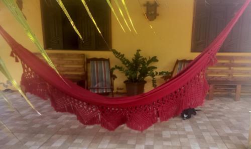 a red hammock in a room with a potted plant at Casa na Praia de Saquaira - Península de Maraú. in Marau