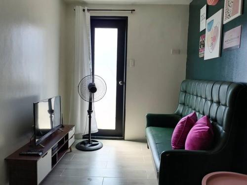 ein Wohnzimmer mit einem grünen Sofa und einem TV in der Unterkunft StayPlus Metro Eclectic Glam 1BR in Manila