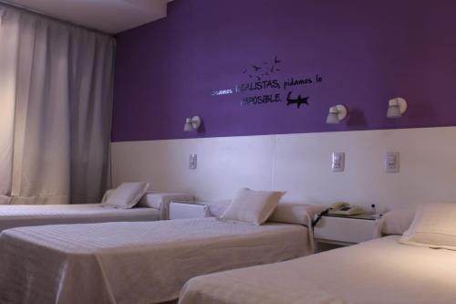 Hotel Ychoalay Caz في ريكونكيستا: غرفة بثلاث اسرة وجدار ارجواني