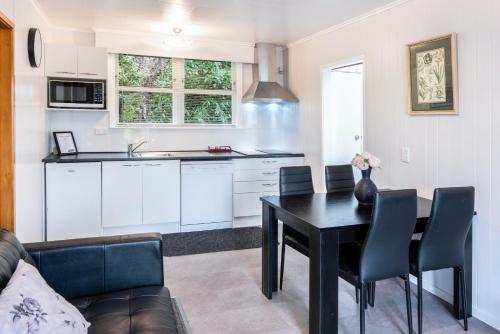 a kitchen and dining room with a black table and chairs at Dunrovin Motel in Taupo