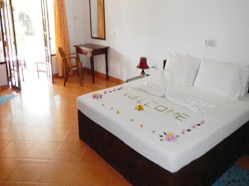- une chambre avec un grand lit blanc orné de décorations dans l'établissement Hotel Sun and Sea, à Bentota