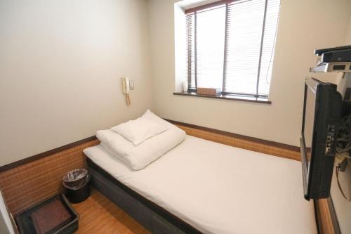 a small room with a bed with a window at プチホテル　コスモス in Tokyo