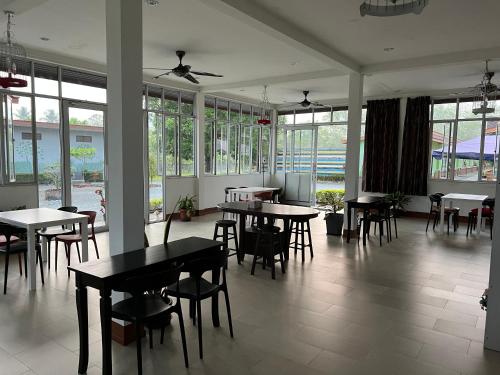 a dining room with tables and chairs and windows at De Langkawi Resort and Convention Centre in Kuah