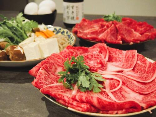 a table topped with plates of food with meat and cheese at サウナ・ジャグジー・完全貸し切りという贅沢　大人の秘密基地　Tiny Cabin TATEGU#02 in Miyota