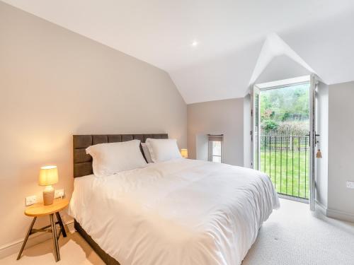 a white bedroom with a large bed and a window at Nixey Cottage in Turville