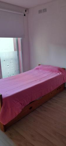 a bed in a room with a pink comforter at Terraza a la Barda in Neuquén