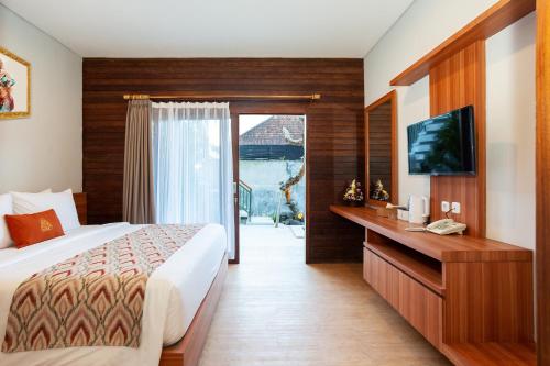 Habitación de hotel con cama y TV en Paisa Ubud en Ubud