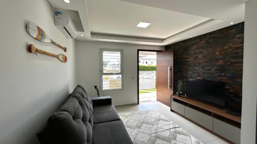 a living room with a couch and a flat screen tv at Casa em Floripa - 200m da praia in Florianópolis