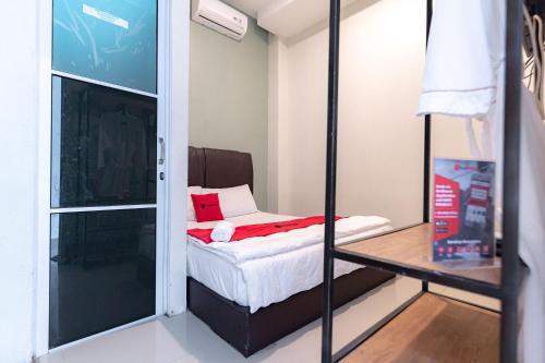 um pequeno quarto com uma cama e uma porta de vidro em RedDoorz near Hang Nadim Batam Airport em Nongsa