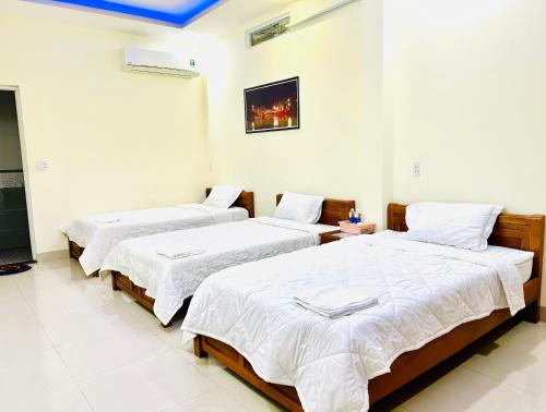two beds in a room with white walls at MyMy Motel in Da Nang