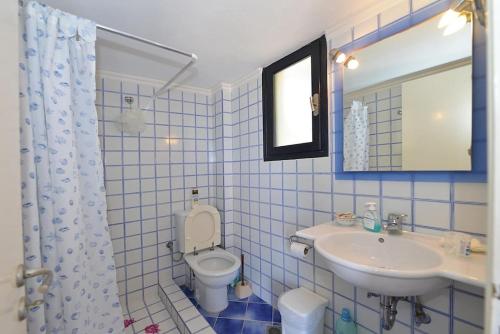 a blue tiled bathroom with a toilet and a sink at Icarus home in Kouniádhoi