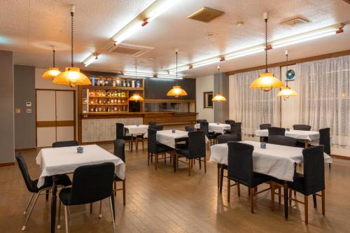 een eetkamer met witte tafels, stoelen en verlichting bij Elan Hotel Lake Nojiri in Shinano