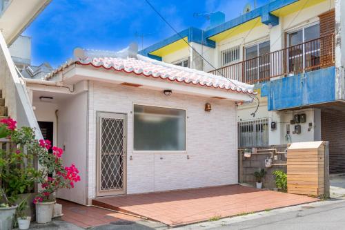 a house with a garage in front of some buildings at 赤瓦のちいさなお家 in Tunugusuku