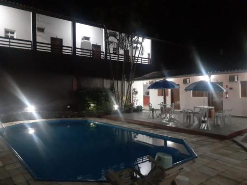a swimming pool in front of a house at night at Pousada Por do Sol in Cananéia