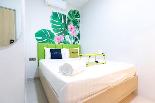 a bedroom with a white bed with a green headboard at Urbanview Hotel R House Batam by RedDoorz in Jabi
