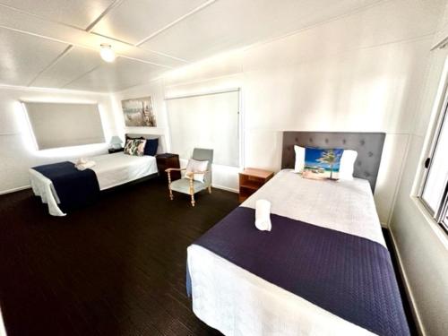 um quarto de hotel com duas camas e uma cadeira em Seacrest on Bright em Emu Park