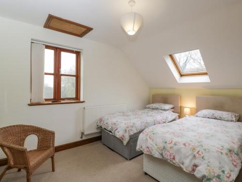 a bedroom with two beds and a chair and a window at Penrose Cottage in Gilwern