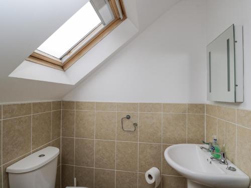 a bathroom with a sink and a toilet and a window at Penrose Cottage in Gilwern