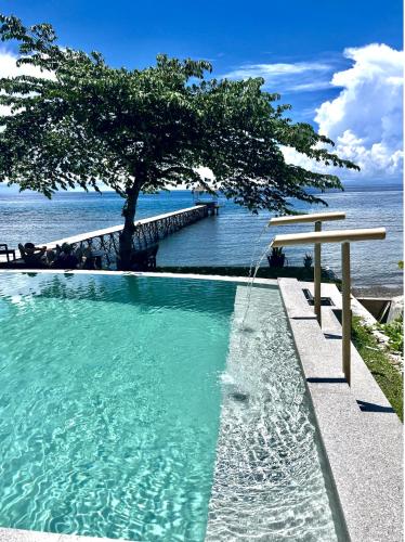 a swimming pool with a tree next to the water at Sanctum Una Una Eco Dive Resort in Pulau Unauna